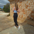 schwarze blickdichte SERILYA ELYA Allure Leggings, blickdicht, Rückansicht vor Natursteinmauer