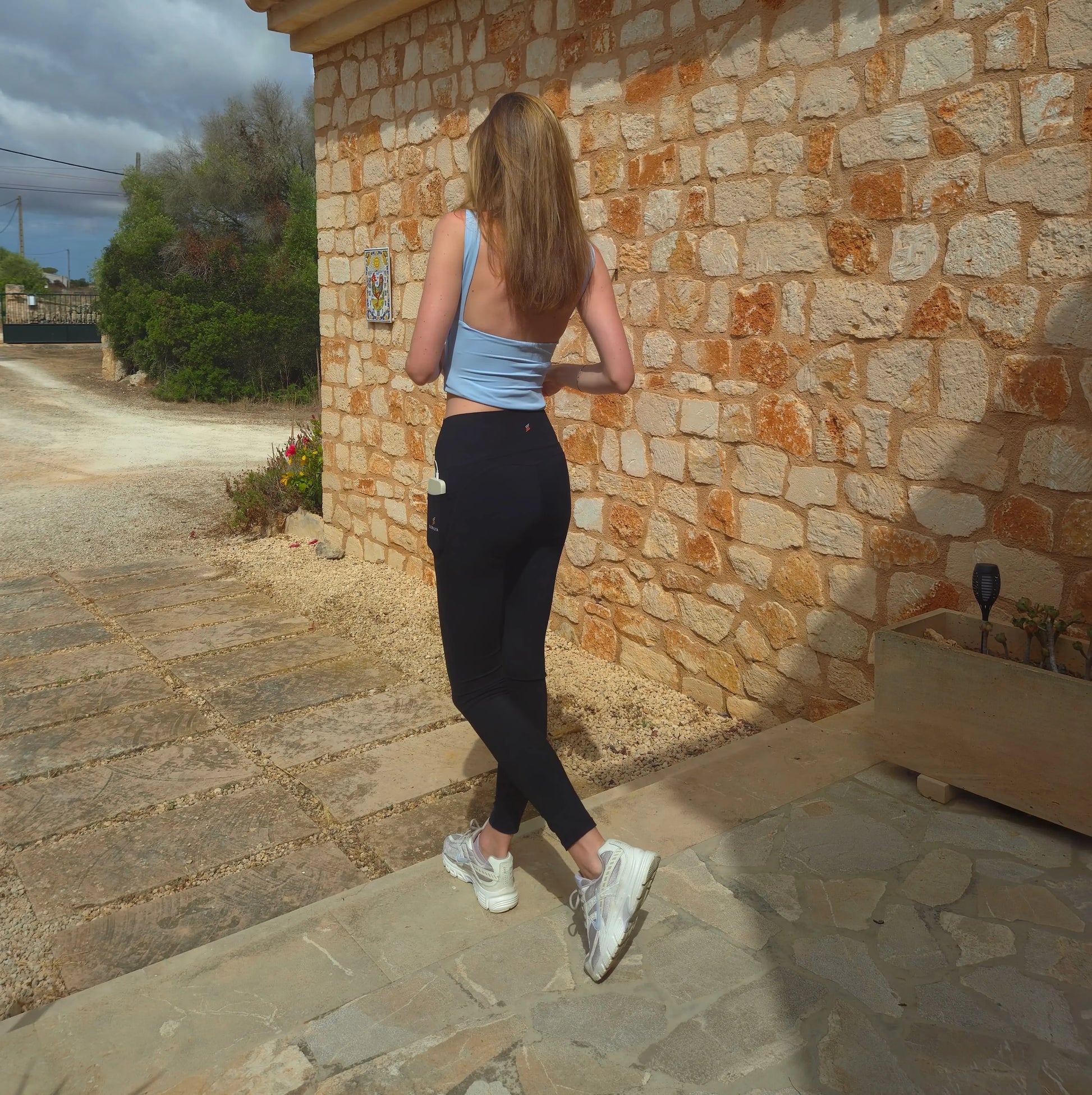 schwarze blickdichte SERILYA ELYA Allure Leggings, blickdicht, Rückansicht vor Natursteinmauer